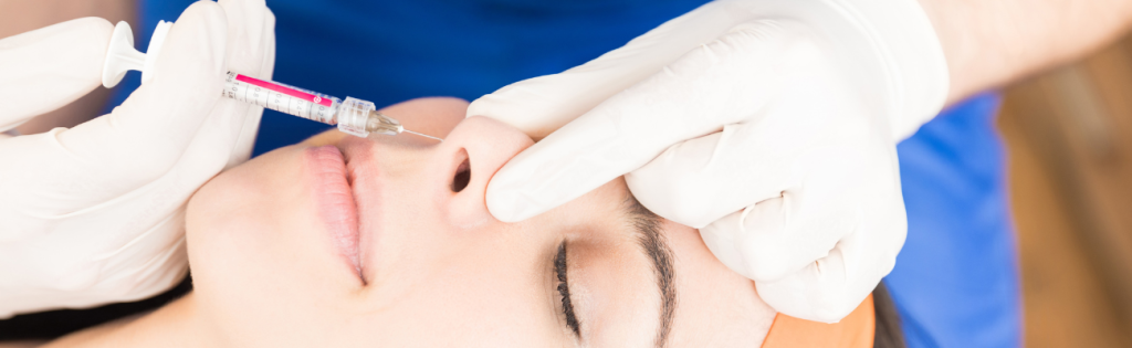 Non-Surgical Rhinoplasty: A Comprehensive Guide to the Procedure, Benefits, Cost, and Side Effects 2 aesthetic practitioner injecting dermal fillers in a patient's nose.