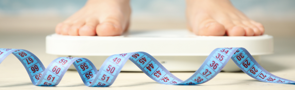 Woman standing on a scale and checking her weight at home.