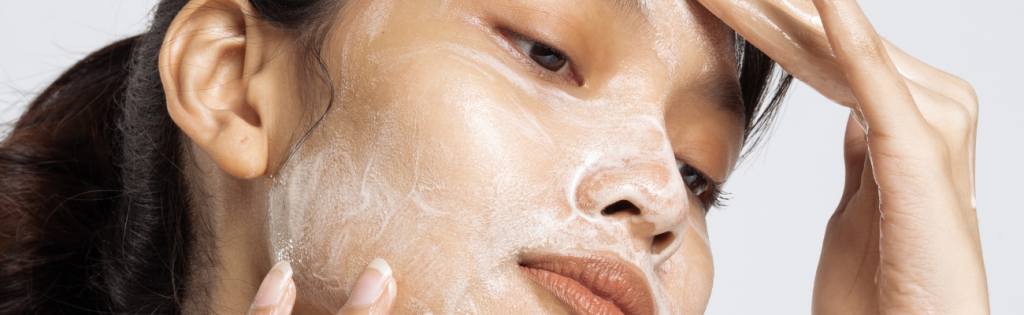 How Your Medical History Can Improve Aesthetic Results 2 Woman applying facial cleanser as part of her skincare routine in a bathroom setting.