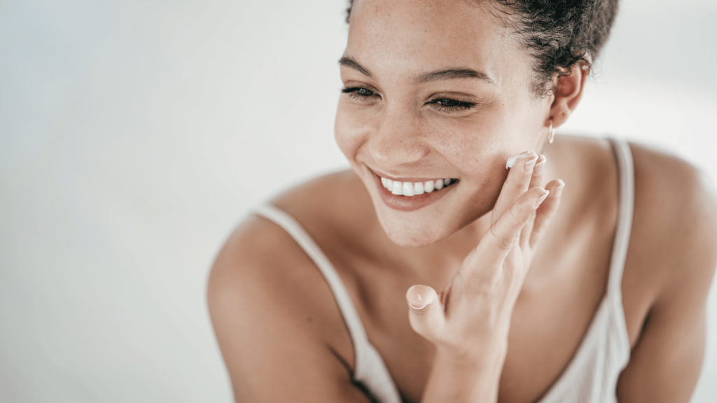Woman applying retinol cream to her face as part of her evening skincare routine.