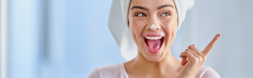 Woman gently applying retinol cream to her face during a nighttime skincare routine.