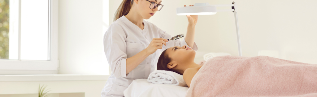 Aesthetic practitioner closely examining a client’s face before treatment.