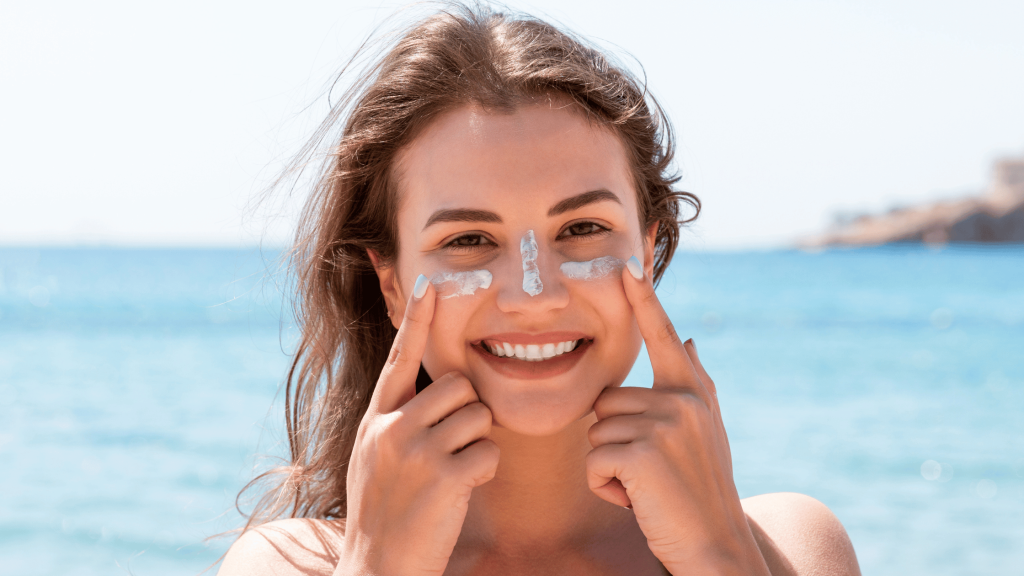 A women on a beach with sunscreen on her face.